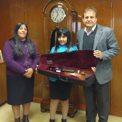 Melina Vallejo, estudiante de música de 10 años, recibe la donación de un violín, junto a su madre Miriam Molina.